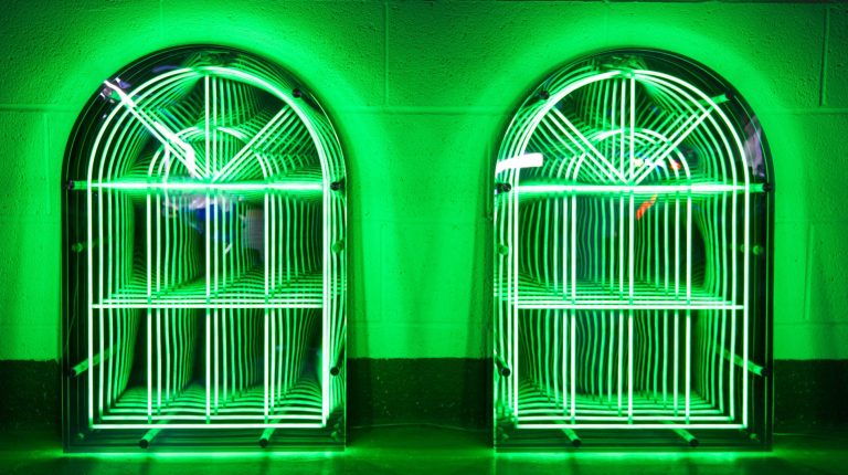 Green LED illuminated infinity archway shelves against a dark background.